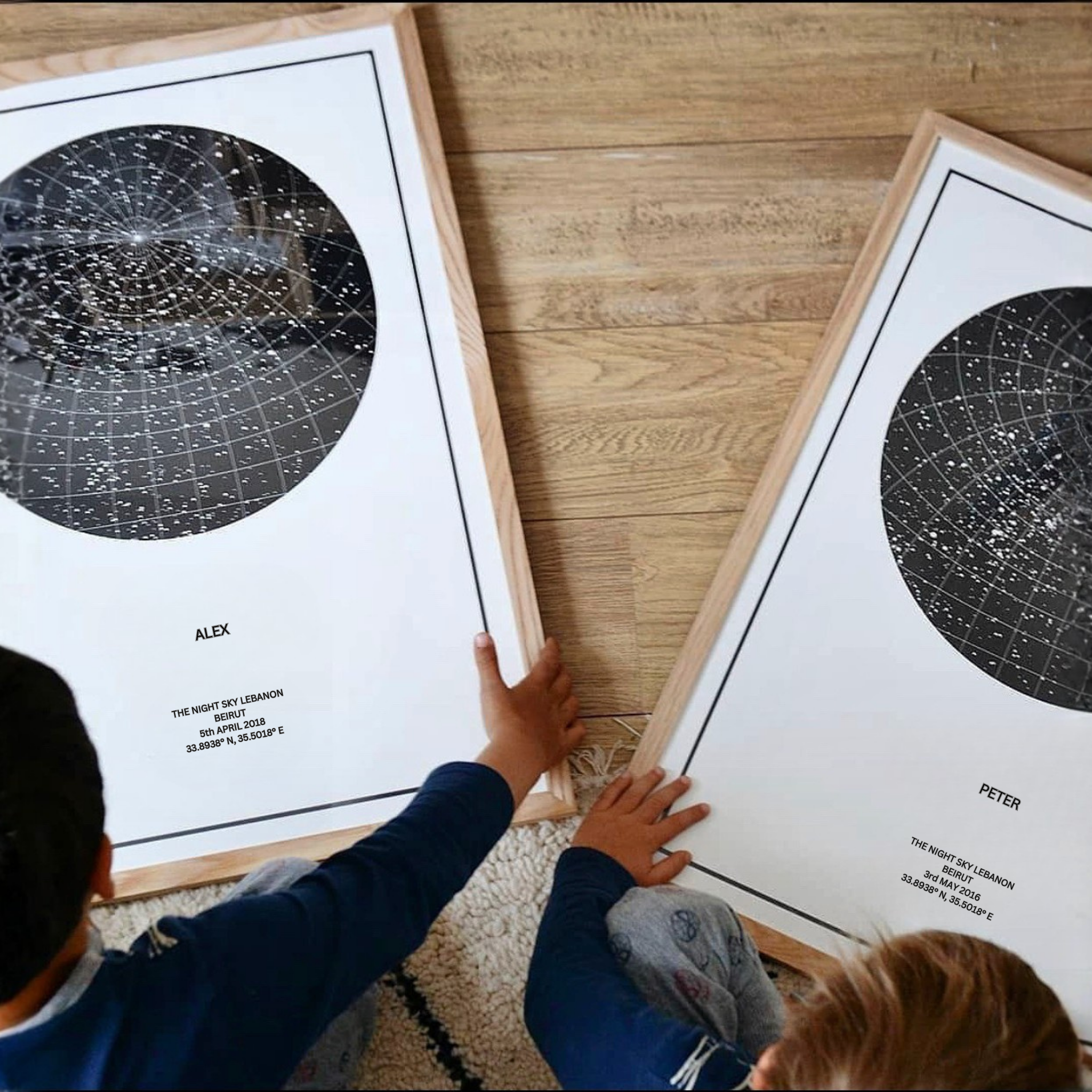 2 young boys sitting on the ground with a star map in front of each.