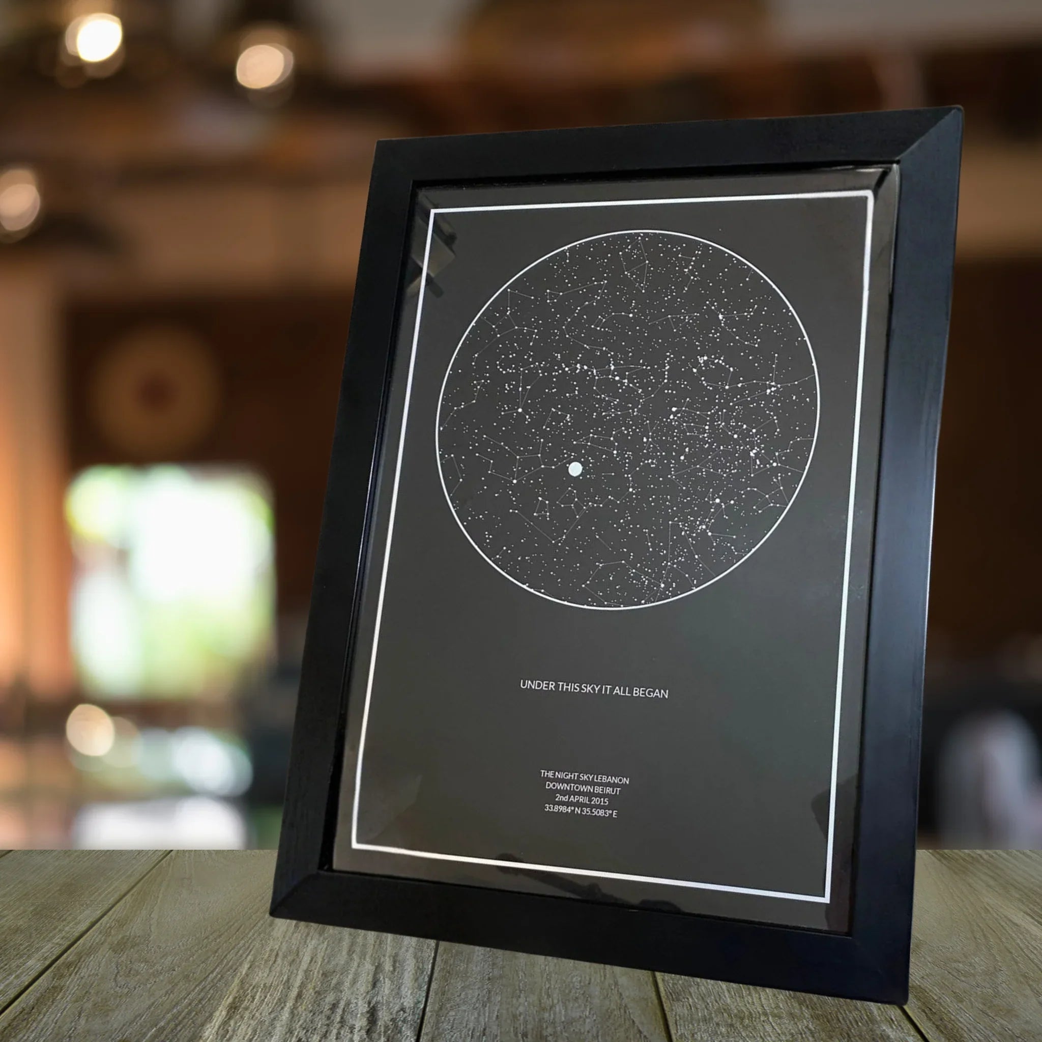 Framed personalized star map print showing a night sky constellation design on a table
